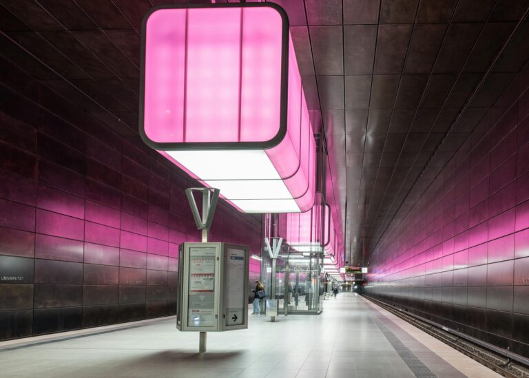 Futuristic train station in Hamburg with striking pink lighting and modern design.