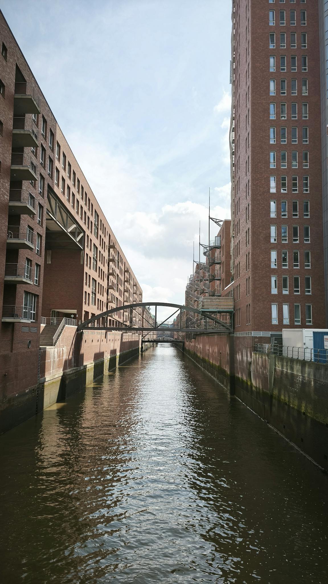 Stunning view of the iconic Speicherstadt canal, flanked by brick buildings and clear skies in Hamburg.